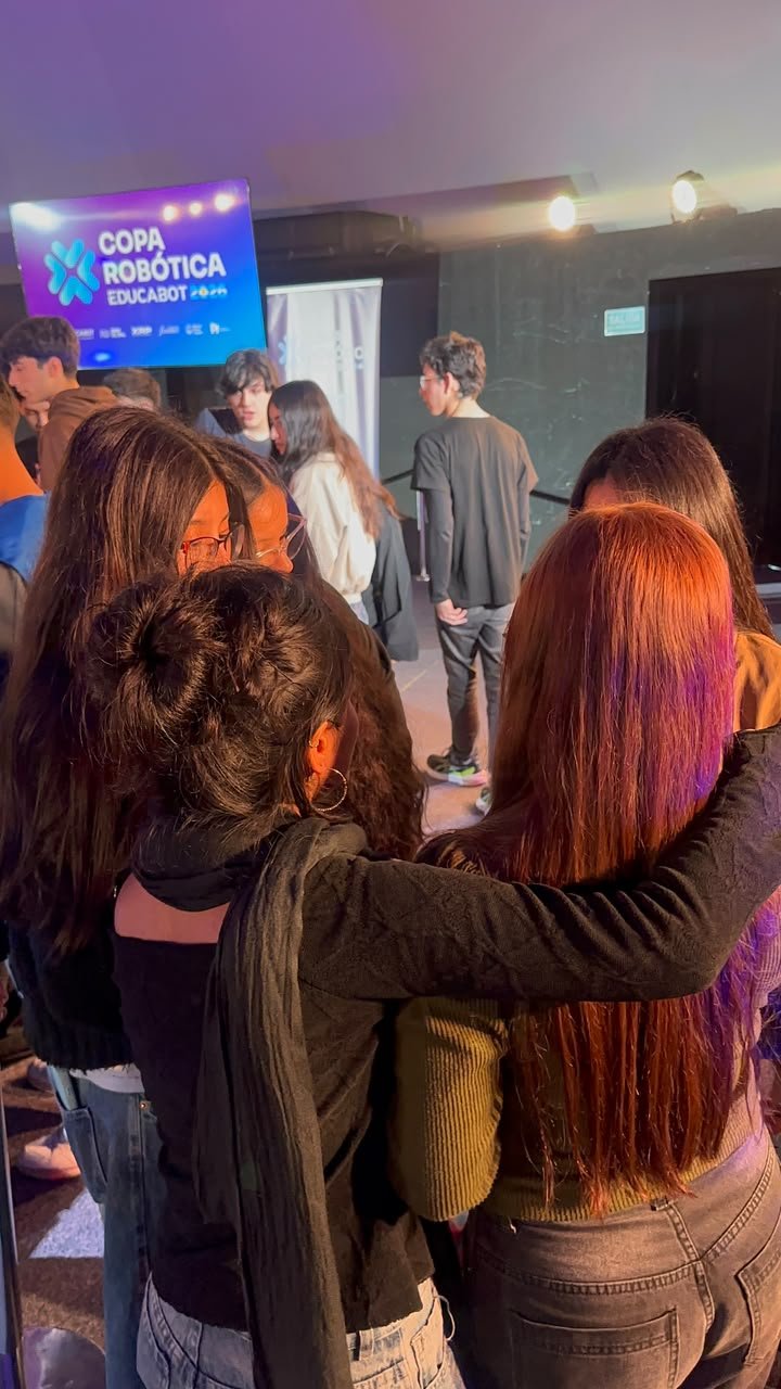 Las alumnas del equipo de Fátima abrazadas, de espaldas, frente a la pantalla de la Copa Robótica Educabot 2026