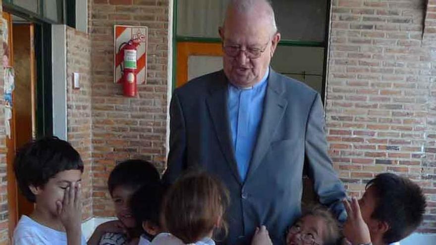 El padre Leoncio Herrero sonriendo, rodeado de chicos de la escuela